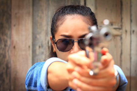 The woman in jeans suit and wearing sunglasses at the shooting range shot from a revolvers,girl and short gun semi automatic,hunting sport equipmentの写真素材