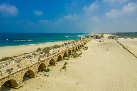 Ruins of the Roman aqueduct arches on the beach of Caesarea Israel with blue see and skyのeditorial素材