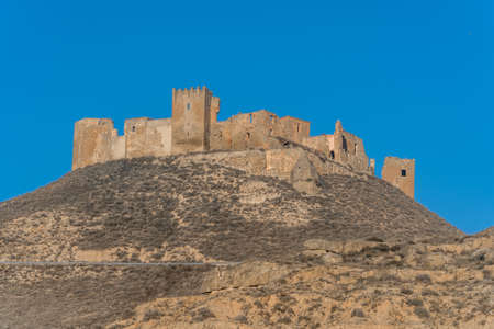 Aerial view of the ruined medieval abandoned Montearagon castle, namesake of the famous kingdom on a bare mountain top near Huesca, Aragon province Spain with blue skyのeditorial素材