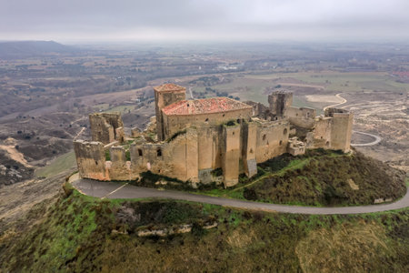 Aerial view of the ruined medieval abandoned Montearagon castle, namesake of the famous kingdom on a bare mountain top near Huesca, Aragon province Spain with blue skyのeditorial素材