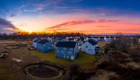 Stunning aerial shot of a cul-de-sac enclave neighborhood street houses with colorful orange yellow purple blue sunset sky in the East Coast United Statesの写真素材