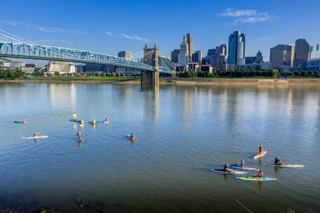 View of Cincinnati downtown skyline with skyscrapers and people kayaking on the Ohio river from Covington and Newport Kentuckyのeditorial素材