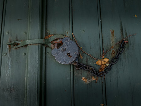 Historic rustic metal lock with chain on a green wooden doorの写真素材