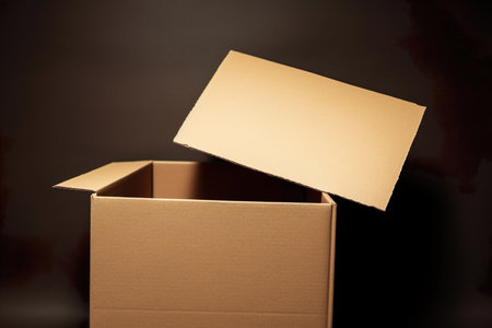 Open cardboard box on a dark background. Shallow depth of field.の素材
