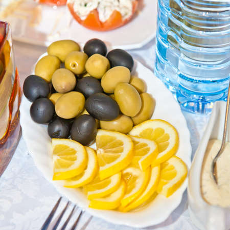 Olives and lemon slices on a plateの写真素材