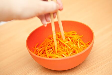 Korean carrots on a plate next to chopsticksの写真素材
