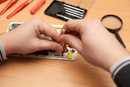Master repairs the tablet computer. Top view of hands working.