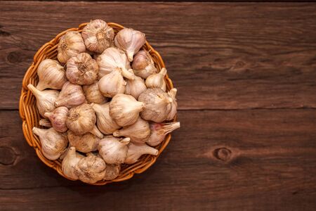 heads of garlic in a wicker basket on a wooden backgroundの写真素材