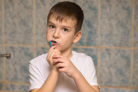 a boy of six is brushing his teeth in the bathroom. close-up portraitの写真素材