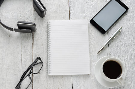 View of business have a notebook, pen, coffee cup, headphones in high definition and mobile phone with on woodden white backgroundの写真素材