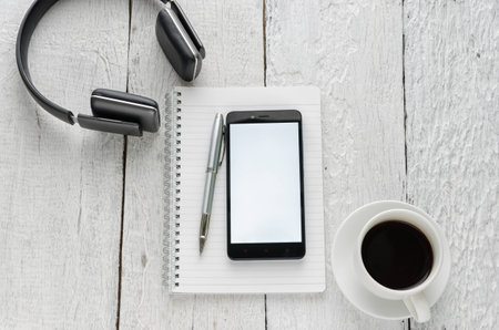 View of business have a notebook, pen, coffee cup, headphones in high definition and mobile phone with on woodden white backgroundの写真素材