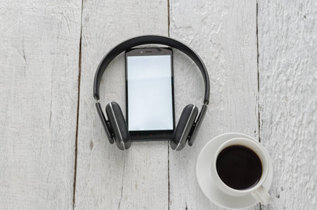 View of business have a notebook, pen, coffee cup, headphones in high definition and mobile phone with on woodden white backgroundの写真素材