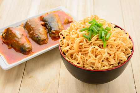 Noodles and canned fish on wooden table.の写真素材