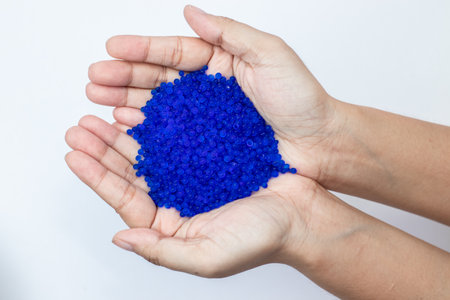 Close up of hand holding blue silica gel on white background, Granular Desiccant attract moisture for chemical.の写真素材