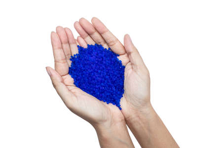 Close up of hand holding blue silica gel on white background, Granular Desiccant attract moisture...