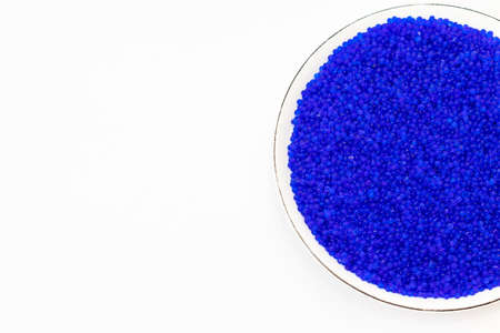 Close up of hand holding blue silica gel on white background, Granular Desiccant attract moisture for chemical.の写真素材