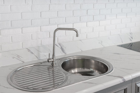 Close Up Silver Tall Faucet and Stainless Steel Sink on Luxury Marble Floor Background In kitchenの写真素材