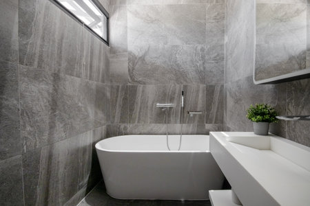Black stone wall bathroom with white bathtubの写真素材
