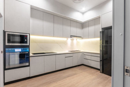Modern white kitchen with black refrigerator in modern homeの写真素材