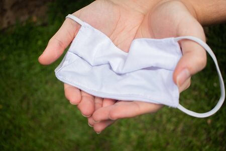 hands holding protection mask with grass backgroundの写真素材