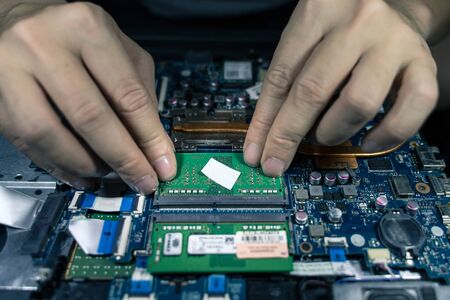 A close-up of an electrician repairing a computer circuit board,close up electrician hands are...