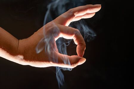 A close up of hand showing and smoky black backgroundの写真素材