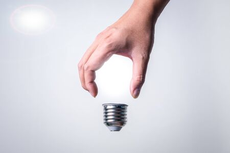 Abstract images concepts of human hands shape into a light bulb and illuminating on a white...