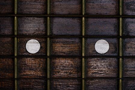 Close-up picture of a guitar with a fingerboard made of wood with a white inlay and a very old...