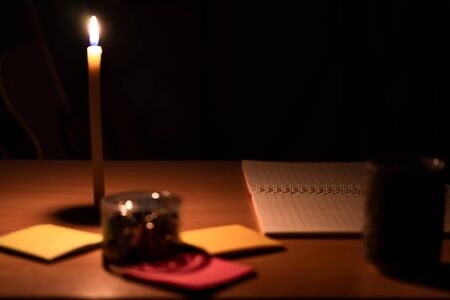 Close-up photos of notebooks and paper clips placed on the table with orange light from candles.の写真素材
