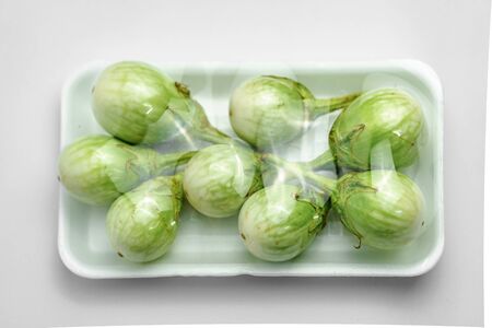 Green eggplant photos in packed in a white foam tray with a white backgroundの写真素材