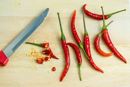 Close-up of chilli and red knives on a wooden floor, meat, fresh food ingredients conceptの写真素材