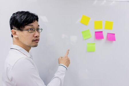A business man pointing his hand to the board with notes