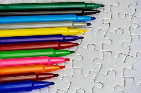 A multicolored pen on a white jigsaw background, color drawing deviceの写真素材