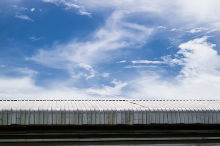 Metal sheet roof building with blue sky background. Steel top part of warehouse or industrial...
