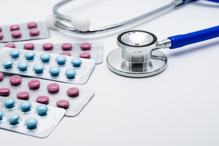 Medical pills, colorful blisters pack with blue doctor stethoscope on white backgroundの写真素材