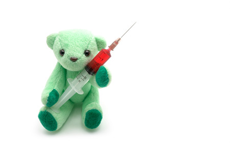 Small green teddy bear holding red injection syringe on white background, children medical conceptの写真素材