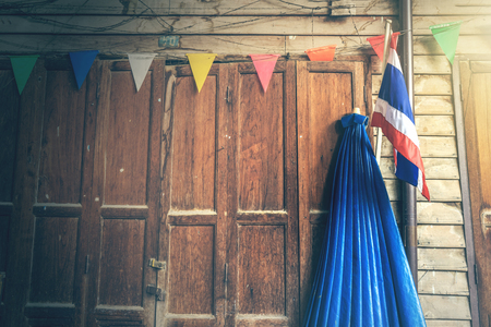 Antique wooden door at vintage Thai house with Thailand flag. Dramatic effect.の写真素材