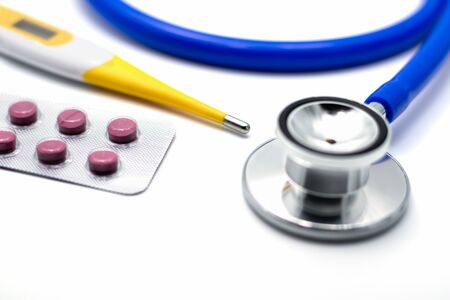 Medical pills, blister pack of pink medicine on doctor desk with thermometer and stethoscope.の写真素材