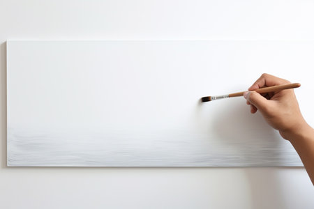 close up hand painting with a paintbrush on white paperの素材