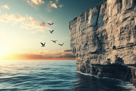 A group of birds flying over the ocean. The sky is a mix of blue and orange hues, creating a serene and peaceful atmosphereの素材