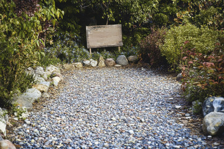 A path with a sign that says "No Parking" in front of a bush. The path is made of gravel and rocksの素材