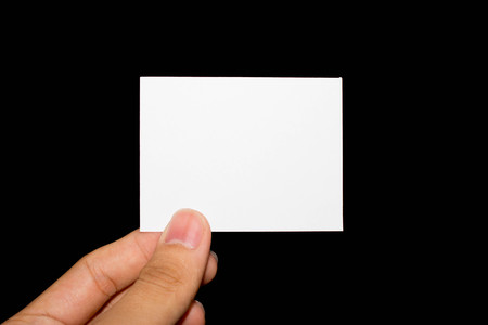 Hand holding blank piece of paper on black backgroundの写真素材