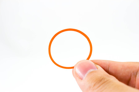 Hand holding a single red rubber band on white backgroundの写真素材