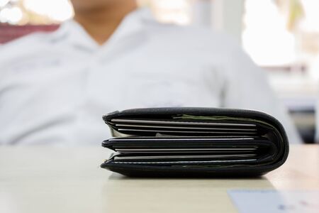 Black thick wallet on wooden table