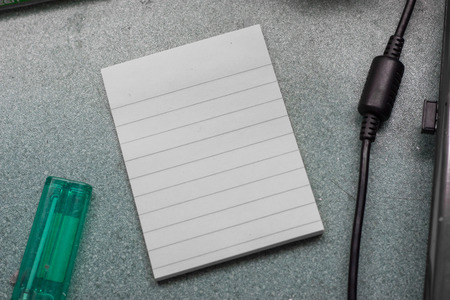 White post it on the table with power cord of laptop