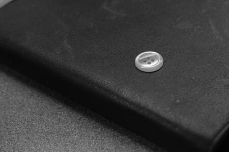 A single white button on black leather wallet