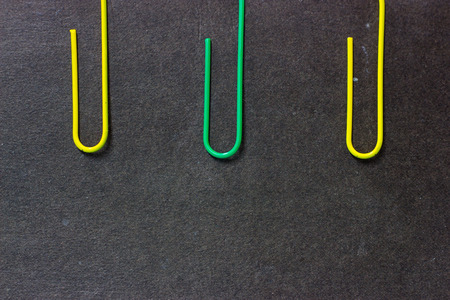 Yellow and green paper clip on black background