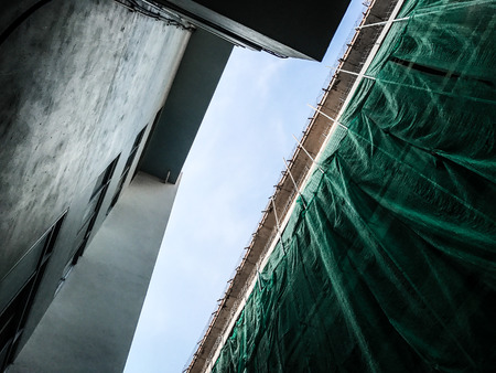 Looking up to the sky between construction buildingの写真素材