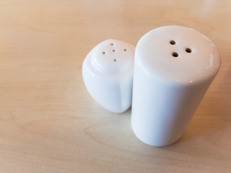 White bottle of salt and pepper on wooden tableの写真素材