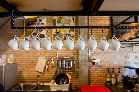 White glass hanging from hanger with blurry background inside coffee shopのeditorial素材